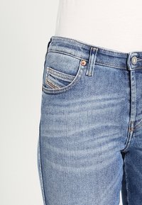 Blå denimjeans med en klassisk design med fem fickor, tvättad i ljus nyans och med kopparfärgade detaljer på knapp och nitar.