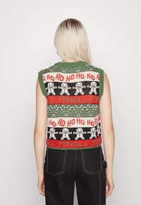 Grüner und schwarzer Strickpullover-Weste mit rotem "Ho Ho Ho"-Text und Lebkuchenmann-Mustern. Ärmelloses Design mit geripptem Halsausschnitt.