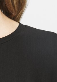Černé tričko s kulatým výstřihem a krátkými rukávy, s hladkou strukturou a jednoduchým, minimalistickým designem.