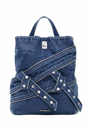 Blå denim rygsæk med flere diagonale sølv lynlåse og remme med trykknapper, med et lille øverste håndtag og Desigual-logo foran.