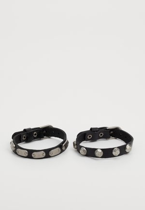 Czarne skórzane bransoletki z metalowymi srebrnymi ćwiekami i heksagonalnymi akcentami, z regulowanymi sprzączkami i gładką fakturą.
