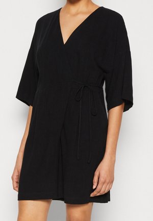 Vestido negro ajustado de tela suave, con escote en V, mangas cortas y cintura anudada para un ajuste adaptable. Textura suave, diseño simple.