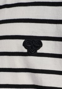 Randigt bomullstyg i svart och vitt med en texturerad, broderad blommig logotyp i svart. De horisontella ränderna är jämnt breda.