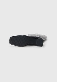 Scarpe nere a pianta piatta con suola in gomma testurizzata, tomaia in pelle liscia e design a punta quadrata. Presentano un marchio discreto di lato.