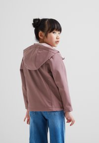 Light pink hooded jacket with a smooth texture, featuring a tied closure and a relaxed fit, paired with blue denim jeans.