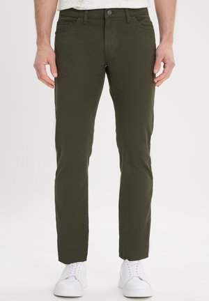 Olive green trousers, slim fit, cotton-blend fabric, front pockets, and a single-button closure, paired with white sneakers.