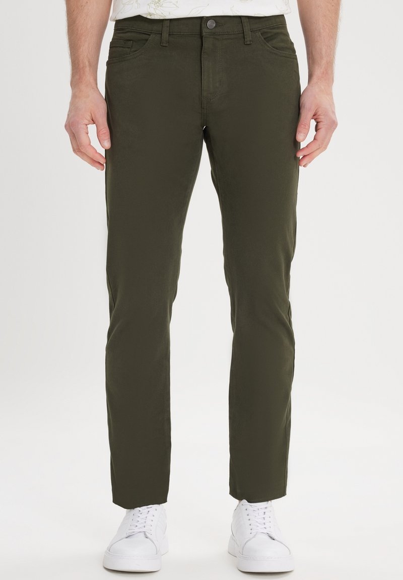 Olijfgroene broeken, slim fit, katoenmix, voorzakken en een enkele knoopsluiting, gecombineerd met witte sneakers.