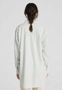 Lichtgewicht, langetermijnshirt met verticale groene en beige strepen, knoopmanchetten en een losse pasvorm met een geplooide rugdetail.