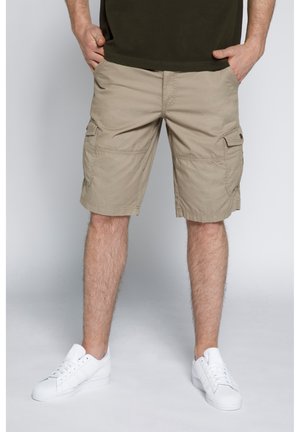Pantaloni cargo beige con più tasche laterali e taglio dritto. Realizzati in tessuto leggero, presentano una trama liscia. Indossati con sneakers bianche.