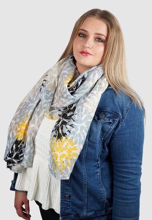Lichtgewicht bloemen sjaal met een grijs, wit en geel patroon. Gemaakt van zachte stof met een vloeiende drape. Draagt over een spijkerjack.