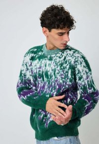 Pull en tricot présentant un motif tie-dye en vert, blanc et violet. Tissu texturé avec poignets et col côtelés. Coupe décontractée.