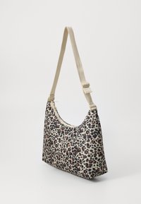 Sac à épaule en imprimé léopard beige, avec une texture de tissu douce, une forme incurvée, une bandoulière ajustable de couleur crème et des accents en doré.