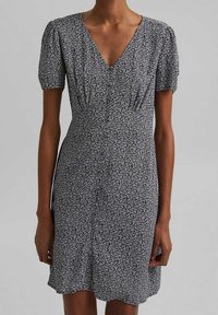 Schwarz-weißes Blumenkleid mit kurzen Puffärmeln, V-Ausschnitt, tailliertem Oberteil und leicht ausgestelltem Saum. Weicher Stoff mit einem zarten Druck.