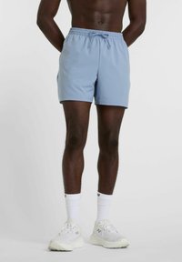 Light blue swim shorts with an elastic waistband and drawstring, featuring a smooth texture and above-knee length. Worn with white sneakers.