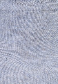 Tessuto a maglia azzurro chiaro con coste visibili e una texture morbida. La superficie presenta leggere variazioni di tonalità e una finitura liscia.