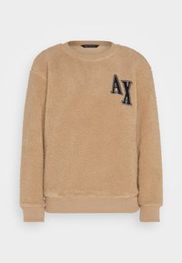 Felpa di pile beige con polsini e orlo a coste. Presenta un logo "AX" nero ricamato sul petto a sinistra. Texture morbida con vestibilità rilassata.