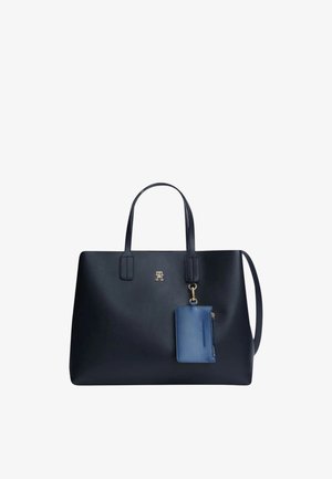 Sac cabas en cuir noir avec deux anses et une petite pochette bleue attachée à l'avant avec un fermoir doré.