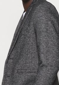 Grijze textuur blazer met een notch lapel, een enkele zak en een sluiting met twee knopen, met een subtiel gemêleerd patroon.