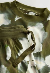 Szara oliwkowa bluza i dopasowane spodnie z kwiatowym wzorem. Teksturowany prążkowany dekolt oraz regulowany pas ze sznurkiem.