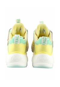 Lime zöld és sárga vastag sneaker, fehér talppal, hálós béléssel és cipzár részletekkel, a sarokon lévő márka logóval és húzófülekkel.