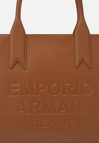 Braune Laptoptasche aus Leder mit geprägtem Branding "EMPORIO ARMANI MILANO." Verfügt über flache Tragegriffe und eine glatte Oberfläche mit minimalen Verzierungen.