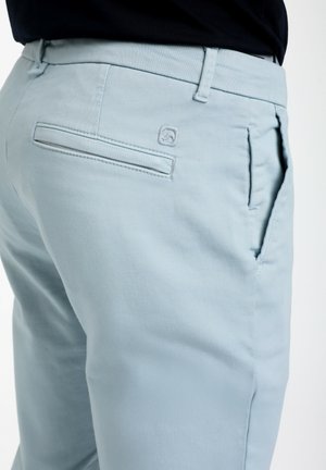 Pantalones de un azul claro, hechos de una suave tela de algodón, con un bolsillo trasero y un pequeño logo de la marca bordado en la cinturilla.