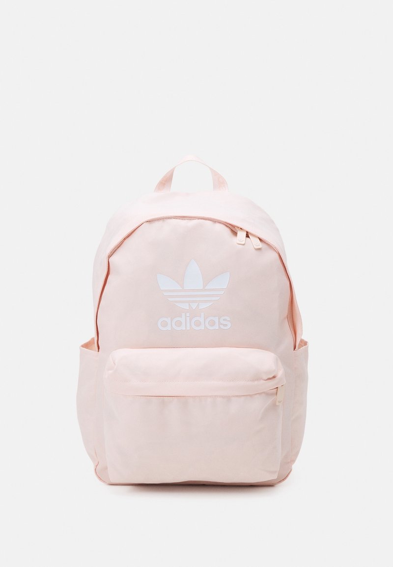 Růžový plátěný batoh s přední kapsou na zip, nastavitelnými popruhy a bílým logem Adidas na přední straně. Hladký povrch, zaoblený tvar.