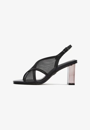 Schwarze Netz-Sandaletten mit offenem Zehenbereich und Slingback, die sich durch sich kreuzende Riemen und einen durchsichtigen Blockabsatz auszeichnen. Verstellbarer Knöchelriemen für einen sicheren Sitz.