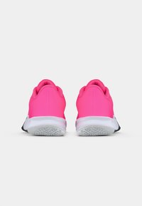Světlé růžové sportovní boty s hladkým materiálem, kulatým podpatkem, bílou mezipodešví a černou podrážkou; minimalistický design bez výrazných vzorů.