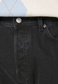 Czarne dżinsy o subtelnej strukturze, z metalowym zapięciem, szlufkami na pasek i prostym krojem.