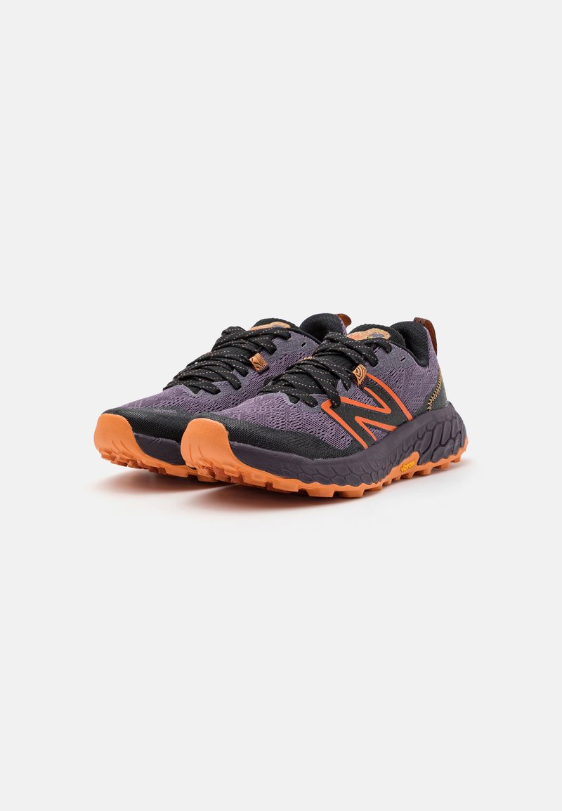 Lila und schwarze Sportschuhe mit orangefarbenen Akzenten, strukturiertem Mesh-Obermaterial, Gummisohle und traditionellem Schnürsystem.