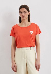 Orange cotton t-shirt with a wide neckline and short sleeves, featuring a white heart graphic with the word "love" inside.