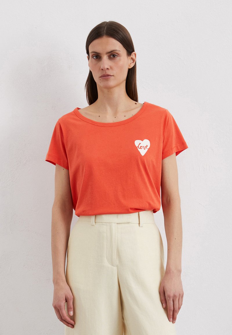 Orange cotton t-shirt with a wide neckline and short sleeves, featuring a white heart graphic with the word "love" inside.