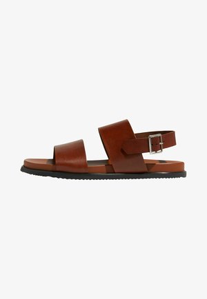 Braune Ledersandalen mit zwei breiten Riemen und einer verstellbaren Knöchellasche. Sie haben eine flache Sohle und eine strukturierte schwarze Gummisohle.