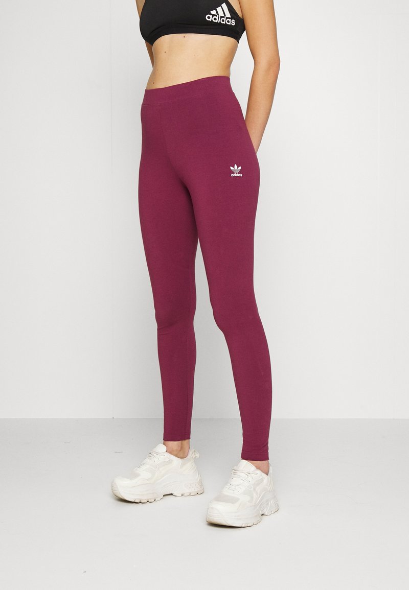 Bordo legingi, kas izgatavoti no elastīgas auduma, ar augsto jostasvietu un mazu baltu Adidas logo uz gurniem. Apvienoti ar baltajiem sporta apaviem.