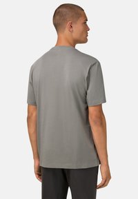 T-shirt gris à manches courtes en tissu lisse, avec un col rond et une coupe décontractée, dotée d'un ourlet droit et sans logos visibles.