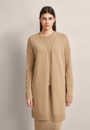 Beige langer Cardigan mit offenem Front, gerippten Bündchen und Saum. Stricktextur mit lockerer Passform, über einem passenden Pullover getragen.