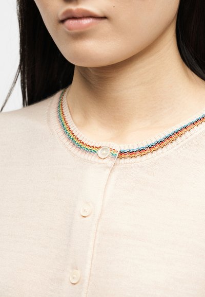 Γυναίκα που φοράει κοντινή λήψη ροζ ανοιχτό ροζ ζακέτα με κουμπιά και πολύχρωμη ριγέ επένδυση γύρω από το λαιμό, κοντινό στο λαιμό και τα χείλη.