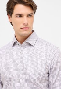 Weiße und helllila gemusterte Button-Up-Bluse mit klassischem Kragen, dezentem Gitterdesign und glänzenden Knöpfen. Glattes Baumwollmischgewebe.