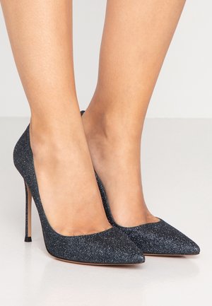 Zwarte glinsterende hoge hakken met een spitse neus, slank ontwerp en dunne stiletto hak; gestructureerd oppervlak met een sprankelende afwerking.