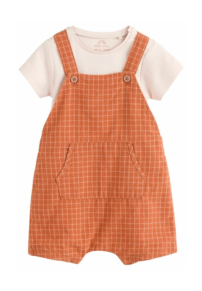Baby overalls i orange med et rutemønster, har justerbare skulderstropper, en stor frontlomme og en hvid bomulds t-shirt under.