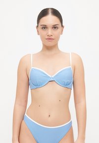 Blå bikinitopp med hvit kant; underwire-design, tynne justerbare stropper, glatt tekstur, kombinert med matchende bikini-bunner.