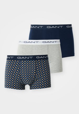 Trois paires de boxers pour hommes : une grise, une bleu marine unis et une bleu marine avec un motif géométrique or et bleu. Ceintures élastiques avec logo.