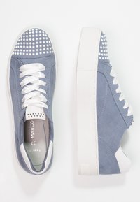 Baskets en daim bleu avec semelles plateformes blanches, lacets en satin blanc et ornements à clous ronds blancs sur la zone des orteils.