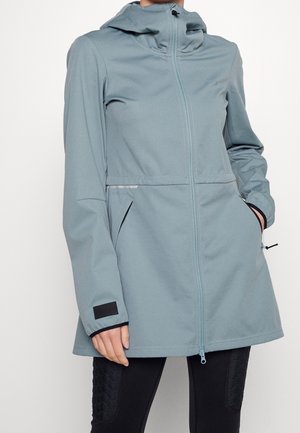 Hellblaue Kapuzenjacke mit Frontreißverschluss, Seitentaschen und verstellbaren Bündchen, getragen über schwarzen Hosen.