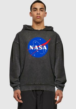 Sudadera negra de tejido texturizado que presenta un gran logotipo azul de la NASA con detalles rojos y letras blancas en el frontal. Corte oversize.