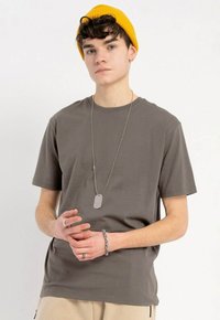 Szara bawełniana koszulka z krótkim rękawem, okrągłym dekoltem i luźnym krojem. W zestawie z żółtą wełnianą czapką i srebrnym naszyjnikiem z identyfikatorem dla psa.