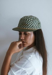 Cappellino da baseball verde con motivo geometrico, dettaglio del logo dorato, texture sottile e stile classico con visiera piatta.