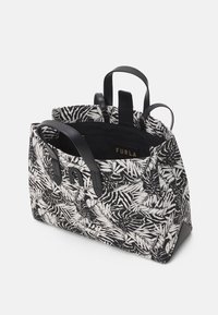 Černobílá vzorovaná taška s texturovanou tkaninou, pevné černé kožené rukojeti a vnitřní štítek s nápisem "FURLA." Design bez víčka.