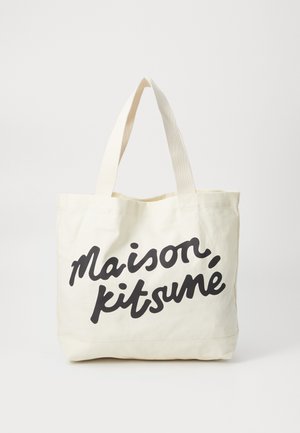 Canvas tote bag in off-white with black script text "maison, kitsuné." Features sturdy handles and a simple design.